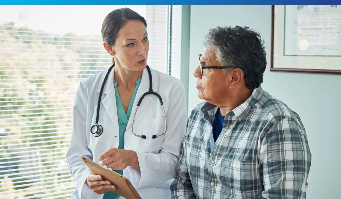 Female doctor reviewing medical information with a male patient during an office visit.