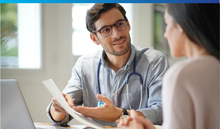 Doctor discussing medical documents with a patient during an appointment in a bright office.